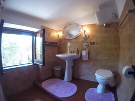Un baño con lavamanos pedestal, inodoro, espejo y ventana.