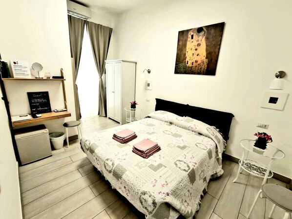 Un dormitorio con una cama, un escritorio, un armario y un cuadro en la pared.