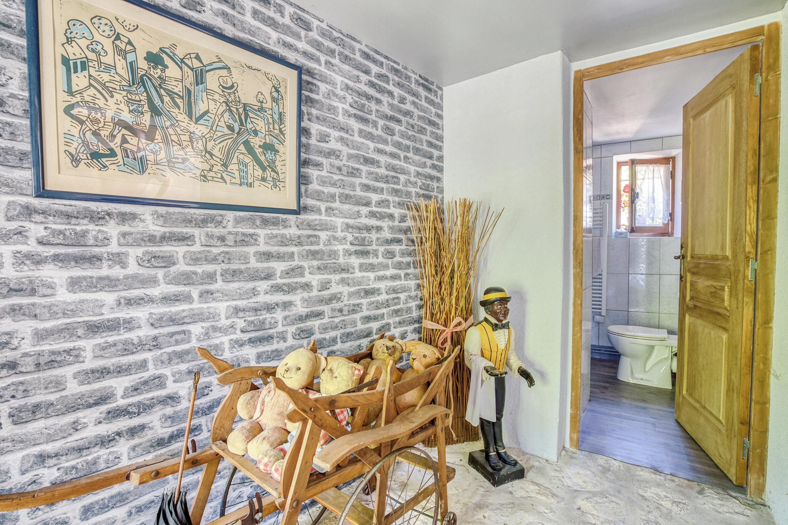 A room with a brick wall, a wooden cart with teddy bears, a statue, and a framed picture.