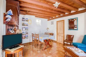 A cozy living room with a television, wooden furniture, a dining area with a table and chairs, and a blue sofa. - Homerez - Peaceful countryside house in Mer (Mer)