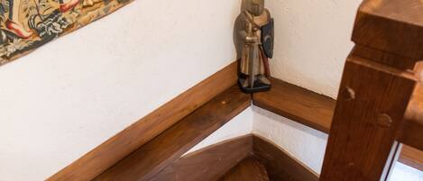 A wooden staircase with a decorative rug and a statue.