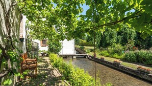 A serene garden with a narrow water channel, a wooden bench, and a white building with a window. - Homerez - Peaceful countryside house in Mer (Mer)