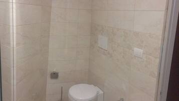 Une petite salle de bain comprenant des toilettes, un bidet et un lavabo.