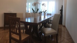 A dining area with a wooden table, six chairs, and two potted orchids. - Robin Rooms (Montegranaro)