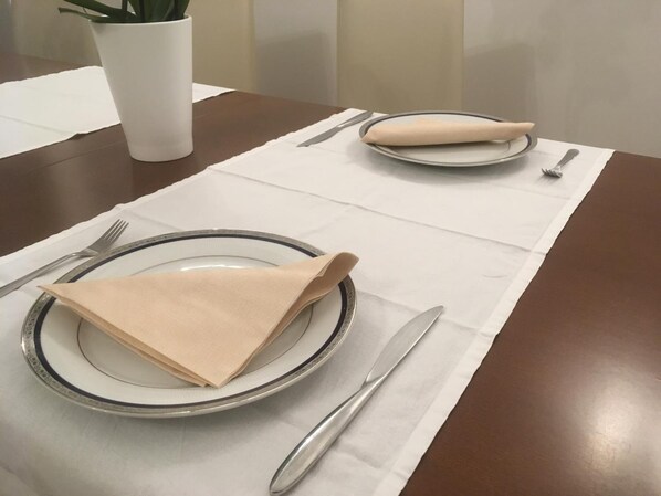 Una mesa de comedor bien dispuesta, con platos, cubiertos y servilletas.