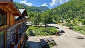 A wooden building with a stone facade, a balcony, and a view of a mountainous landscape.