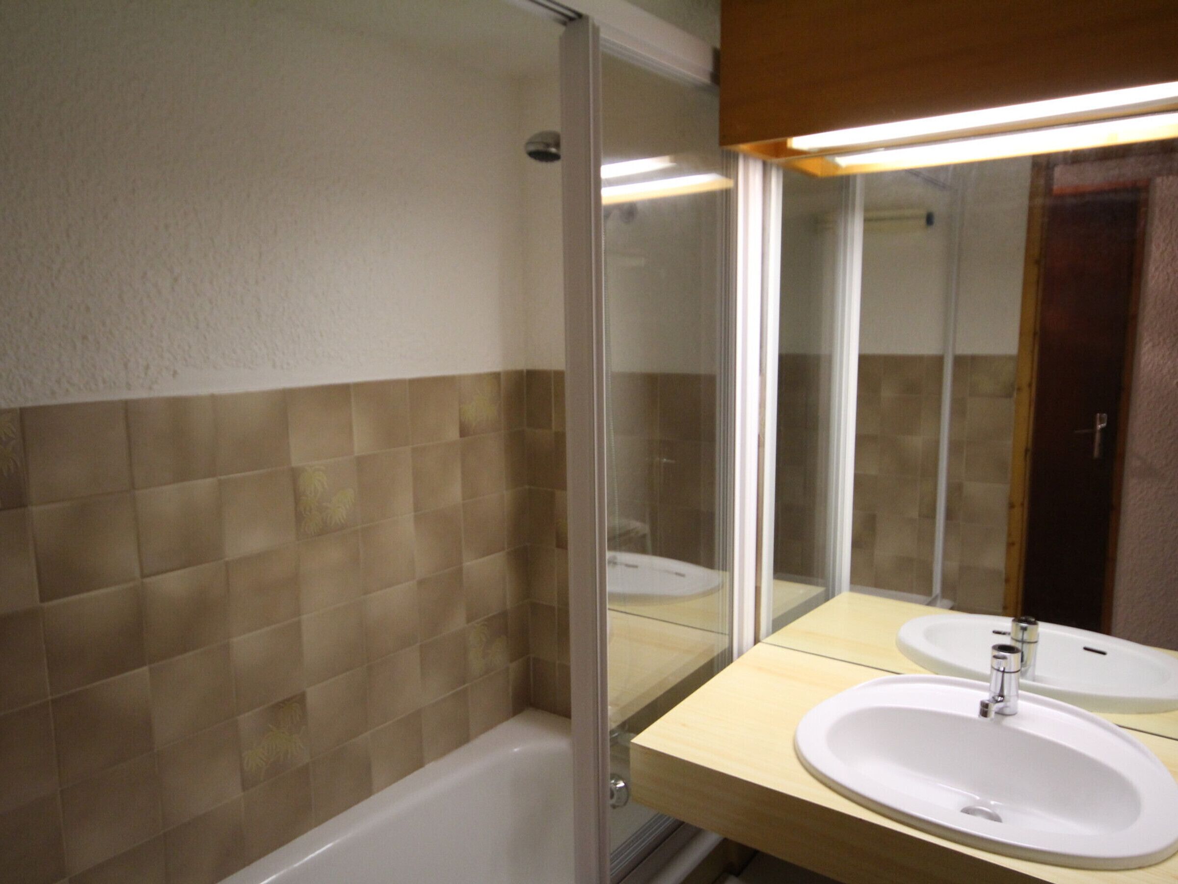 A bathroom with a bathtub, two sinks, and a large mirror.