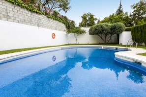 Piscina com parede branca, placa de proibição de mergulho e vegetação ao redor.