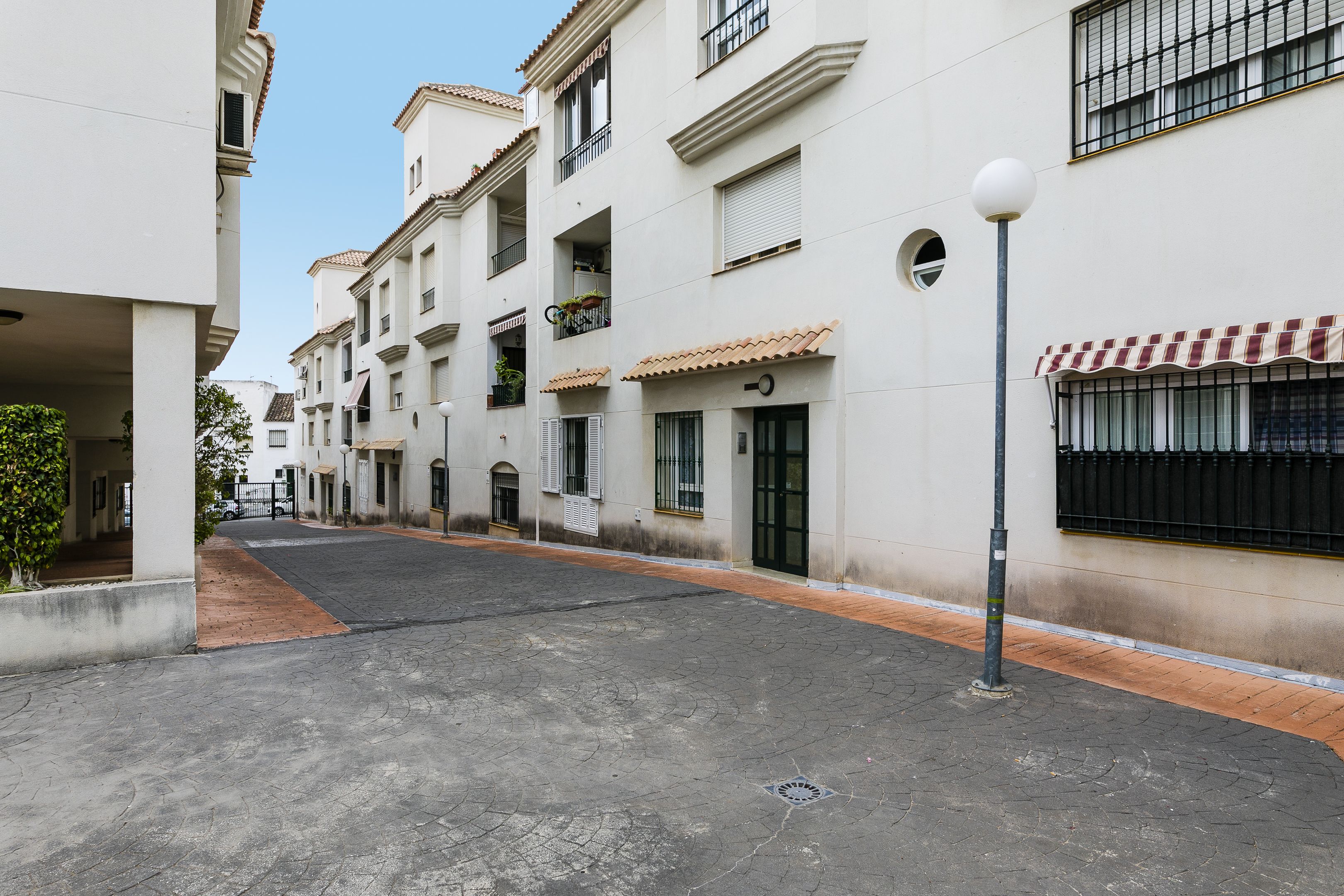 Una calle tranquila con edificios residenciales, una carretera pavimentada y un poste de luz.