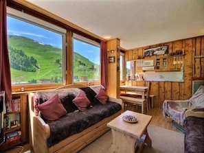 Una cabaña acogedora con sofá, una mesita y una zona de cocina.