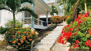 A staircase leading to a building with a covered area, surrounded by lush greenery and flowering plants. - Sunrise Vuth Resort (Koh Rong)