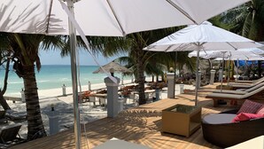 A beachside lounge area with sun loungers, umbrellas, and a view of the ocean. - Sunrise Vuth Resort (Koh Rong)