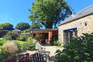 Un bâtiment en pierre doté d’un patio couvert, d’un espace extérieur aménagé pour s’asseoir et d’un jardin.