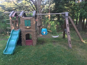 Kids can play and climb on the outdoor play structure featuring a slide, swing, and climbing area.
