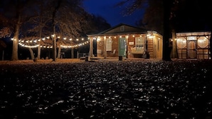 Un chalet rustique doté d’une véranda, de guirlandes lumineuses et d’un espace salon abrité.