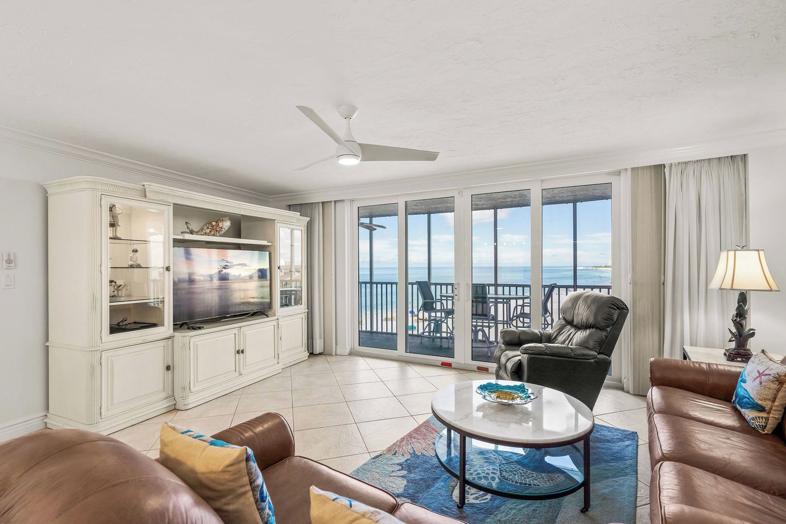 A spacious living room with a television, seating area, and a balcony with a view.