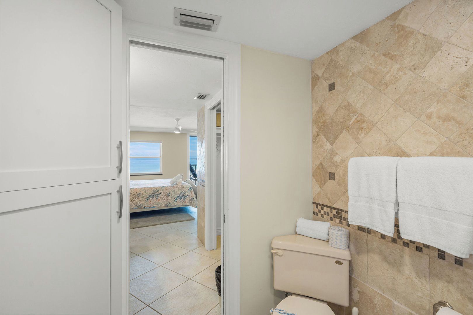 A hotel bathroom with a toilet, sink, and a shower area.