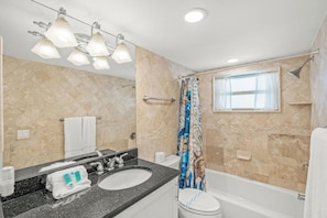 Une salle de bain avec deux lavabos, des toilettes, une douche avec un rideau et une fenêtre.