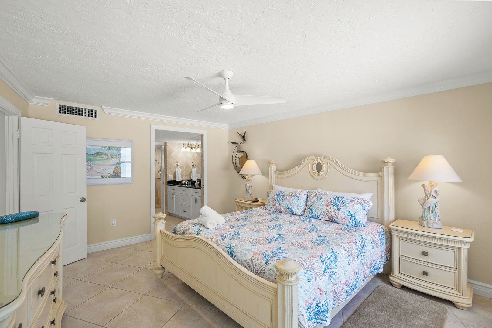 A bedroom with a bed, nightstands, a ceiling fan, and a bathroom visible through an open door.