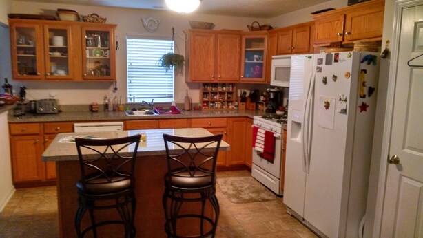 A kitchen with wooden cabinets, a white refrigerator, a stove, and two bar stools. - Cleveland Airport
Bundle yourselves together (Brook Park)