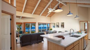 A spacious kitchen with a large island, wooden cabinets, and pendant lighting.