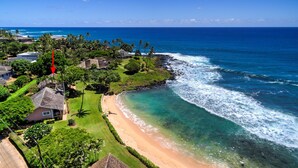 A coastal property with a beach, ocean view, and lush greenery.
