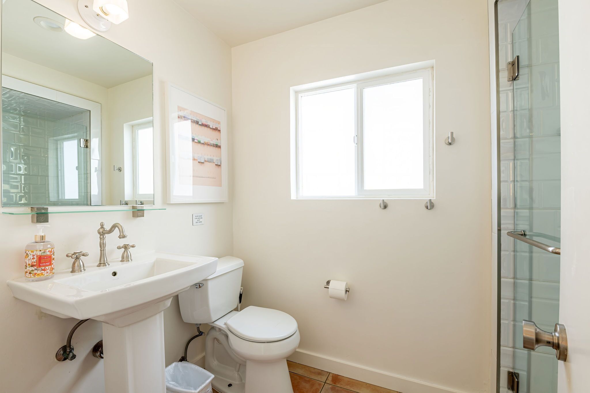 A bathroom with a white sink, toilet, and glass shower enclosure.