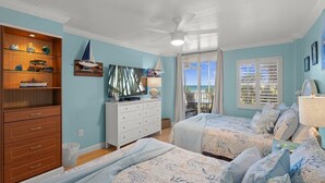 Une chambre avec deux lits, une commode, une télévision et un balcon avec vue.