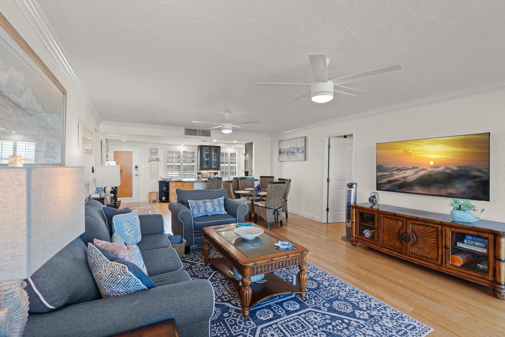 A spacious living room with a grey sofa, a coffee table, and a television on a wooden cabinet.