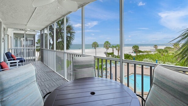 Un balcon avec vue sur la plage, une piscine et un ventilateur de plafond.