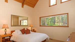 A bedroom with a large bed, two bedside tables with lamps, a mirror, and a window with a forest view. - Excepional spacious lodge 5 min frm Roslyn slps 12, huge loft, WIFI, Hot Tub,  (Ronald)