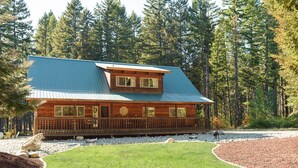 A log cabin with a blue roof, surrounded by a well-maintained lawn and a forested backdrop. - Excepional spacious lodge 5 min frm Roslyn slps 12, huge loft, WIFI, Hot Tub,  (Ronald)