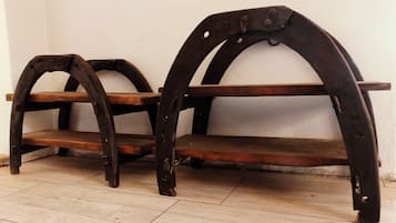 Zwei hölzerne Bänke mit Metallbögen, vor einer schlichten Wand auf Fliesen.