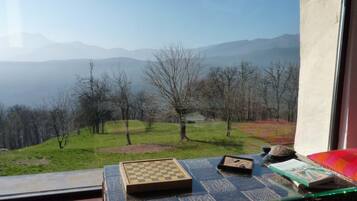 Una habitación con vistas a las montañas, un tablero de ajedrez y un libro sobre una mesa.