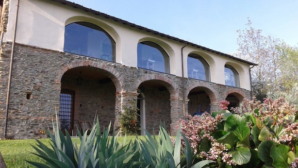 Un edificio con fachada de piedra, múltiples ventanales de arco y techo plano.