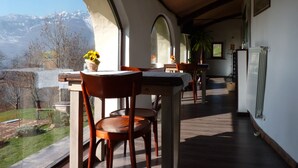 Una habitación con techo de madera, ventanas arqueadas amplias, una mesa de comedor con sillas y vistas a montañas.