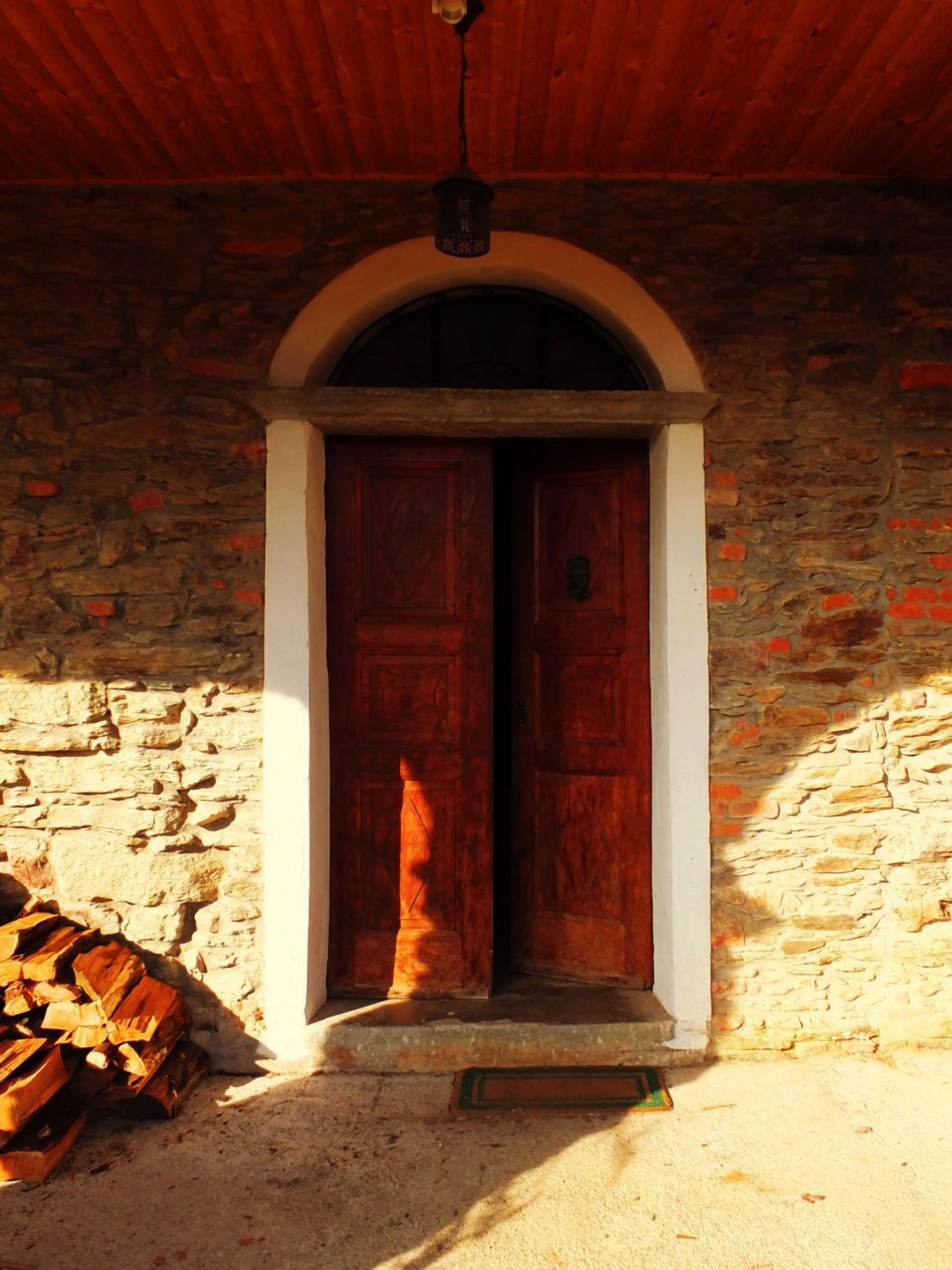 Un edificio rústico de piedra con puerta de madera y un pequeño porche.
