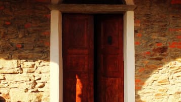 Un edificio rústico de piedra con puerta de madera y un pequeño porche.