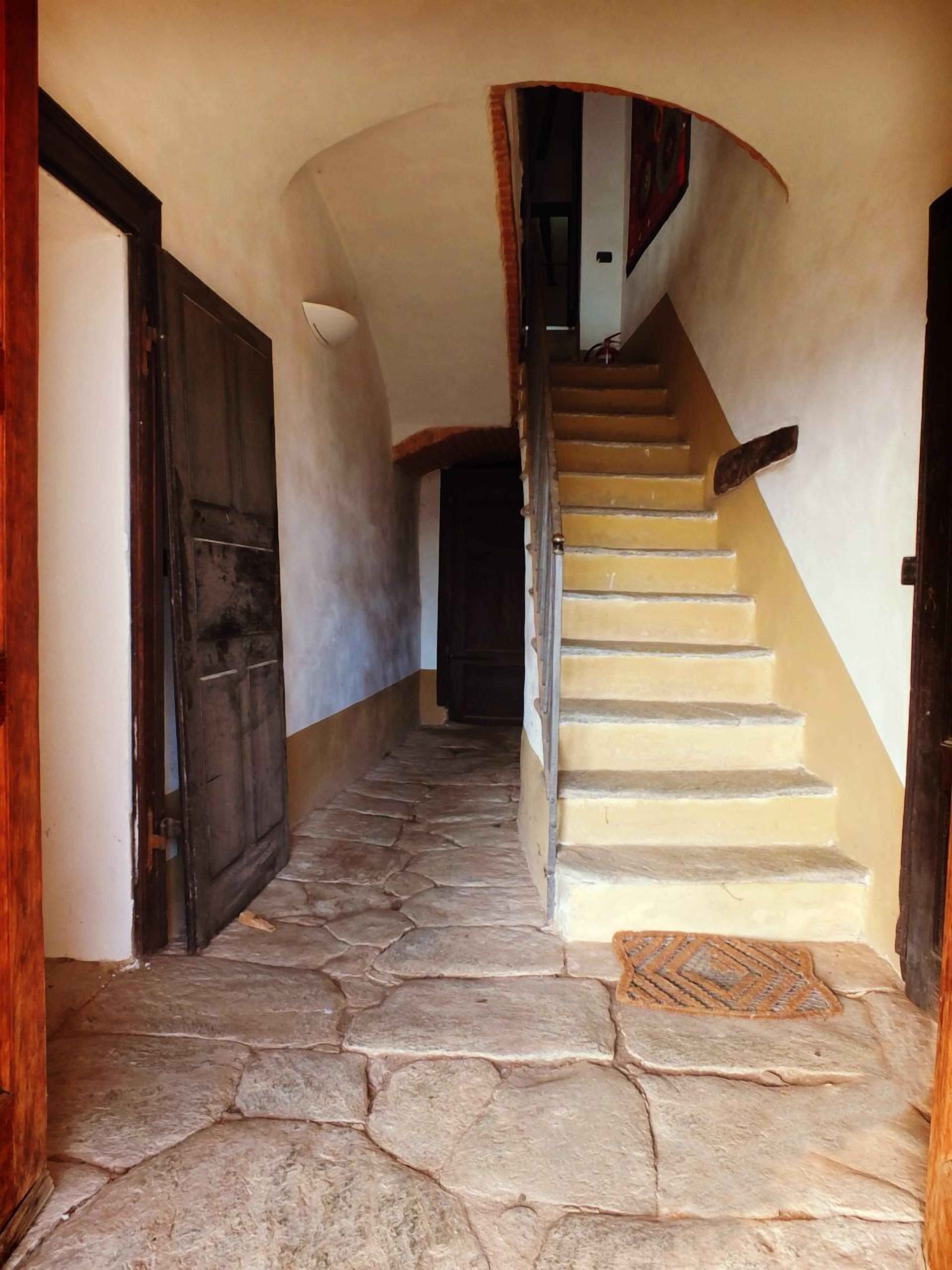 Un escalier en pierre mène à un palier où se trouve une porte, sur la gauche.
