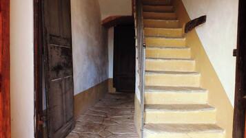 Un escalier en pierre mène à un palier où se trouve une porte, sur la gauche.