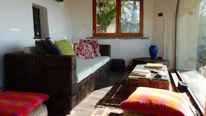 Una sala de estar acogedora con un sofá de mimbre, una mesita y un ventanal con vistas a árboles.