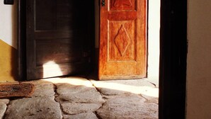 Una entrada empedrada con una puerta de madera y una puerta oscura.