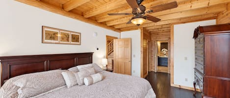 Une chambre avec un grand lit, un plafond en bois et un ventilateur de plafond.