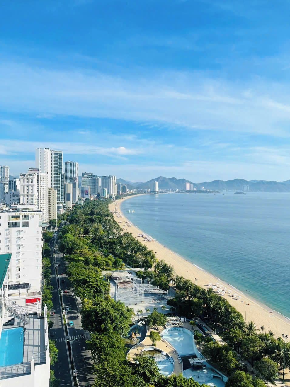 A coastal cityscape with a beach, high-rise buildings, and a clear sky.