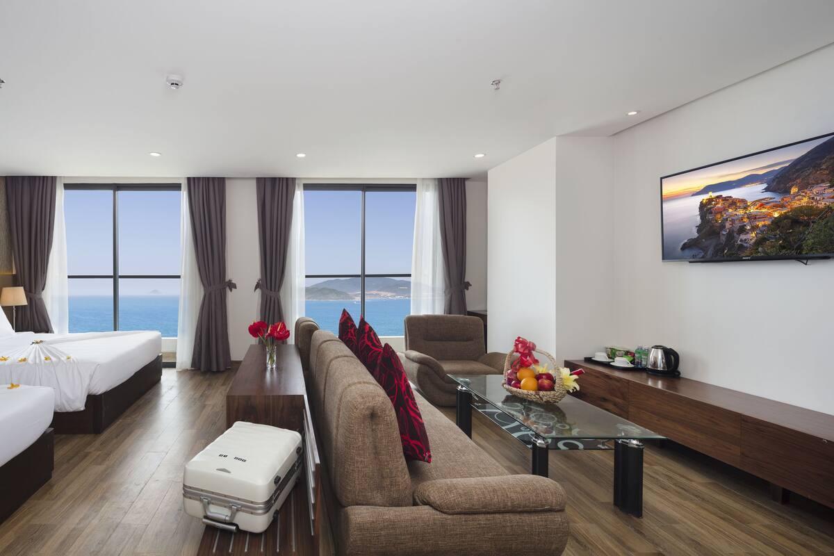 A hotel room with two beds, a sofa, a coffee table, and a TV.