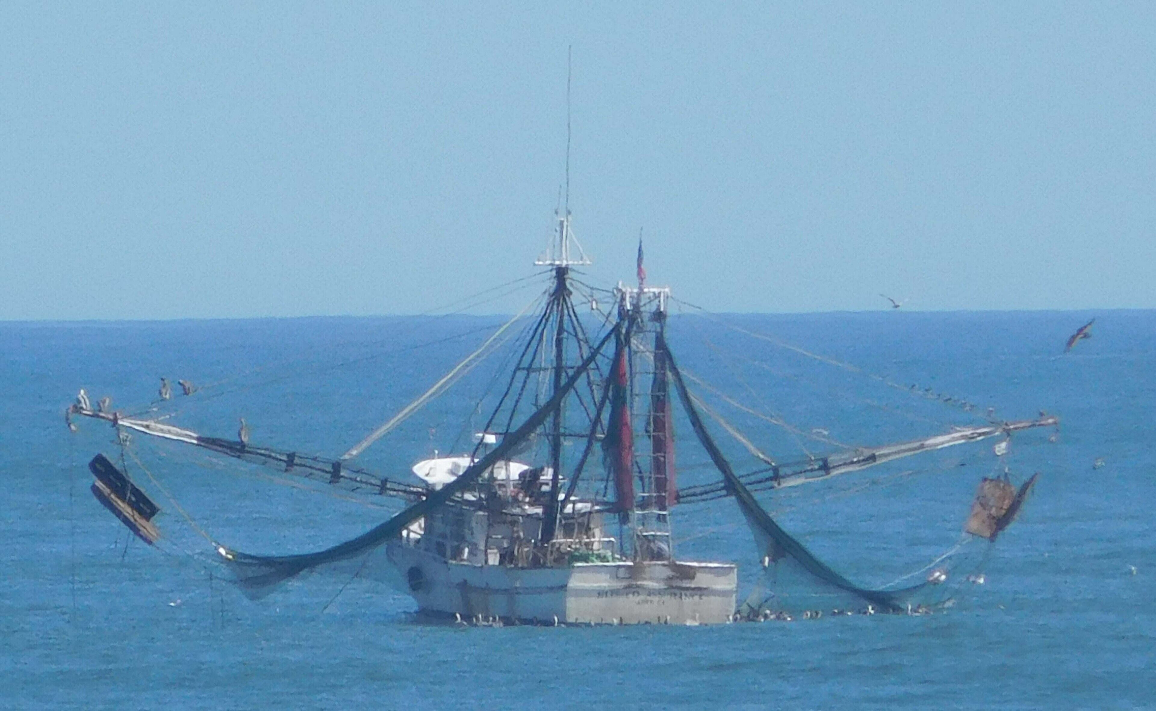 Een vissersboot met een groot net dat zich over het water uitstrekt.