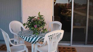 A patio with a table and four white chairs, a potted plant, and a sliding glass door. - SEASIDE ESCAPE ON ST. AUGUSTINE BEACH - WHERE OLD IS NEW AGAIN!!! (St Augustine Beach)