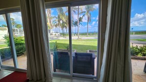 Una habitación con un amplio ventanal corredero que da a un patio con vista a palmeras y un cielo despejado.