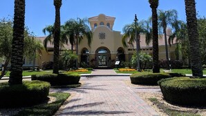 A building with a central entrance, flanked by palm trees and a paved pathway leading to it. - Vista Cay Resort Townhome near Convention/Universal/SeaWorld/Single Greek Golf (Orlando)