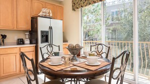 A kitchen with wooden cabinets, a refrigerator, a coffee maker, and a dining table with chairs. - Vista Cay Resort Townhome near Convention/Universal/SeaWorld/Single Greek Golf (Orlando)